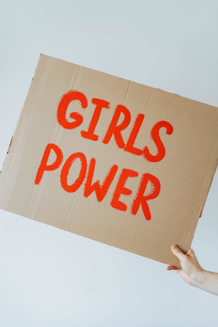 Close-up of a hand holding a cardboard sign with 'Girls Power' text, symbolizing empowerment.